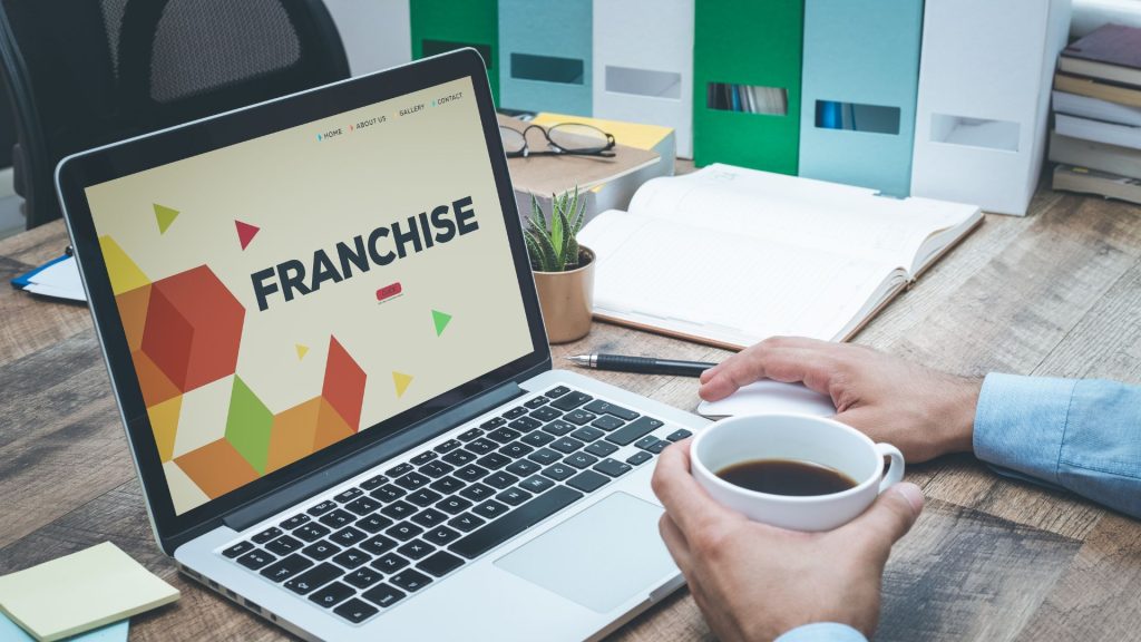 A person's hand touching a screen with the word "FRANCHISE" in a central hexagon.