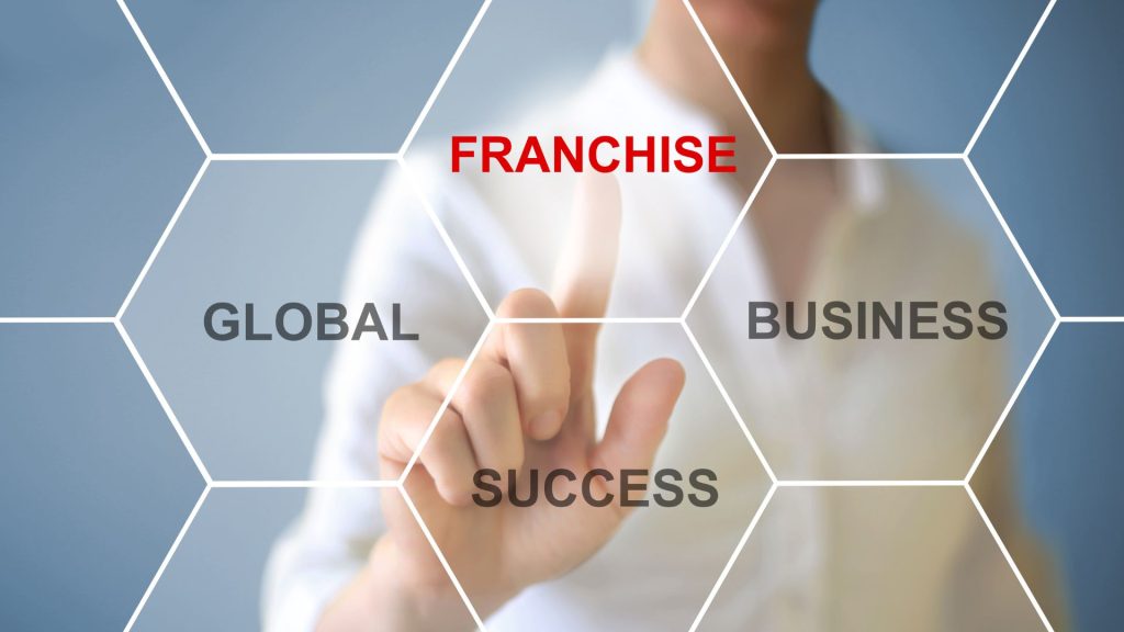 A person looking at a laptop screen that has the word "FRANCHISE" on it.