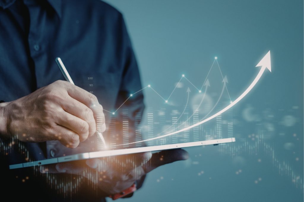 A close-up of a person using a stylus on a digital tablet that displays rising growth charts and glowing arrow trends.